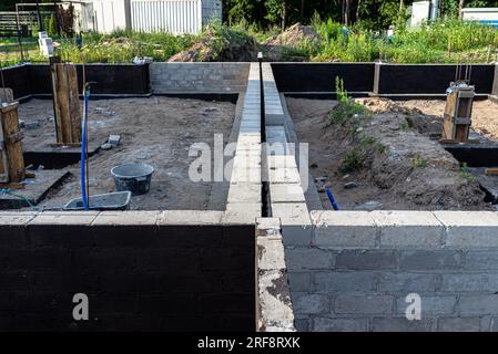 Semelles en blocs de béton peintes avec masse asphalte-caoutchouc de dispersion noire, piliers en béton armé visibles. Banque D'Images