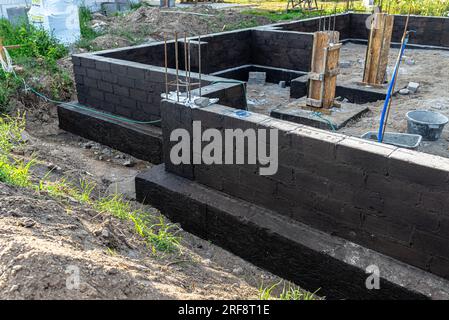 Semelles en blocs de béton peintes avec masse asphalte-caoutchouc de dispersion noire, piliers en béton armé visibles. Banque D'Images