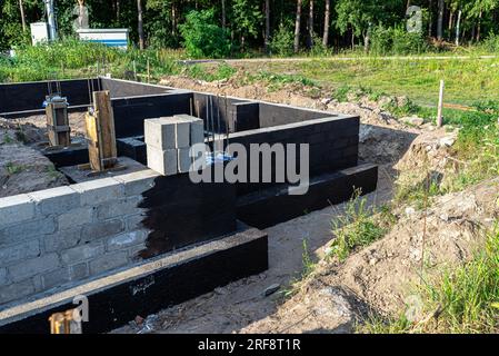 Semelles en blocs de béton peintes avec masse asphalte-caoutchouc de dispersion noire, piliers en béton armé visibles. Banque D'Images