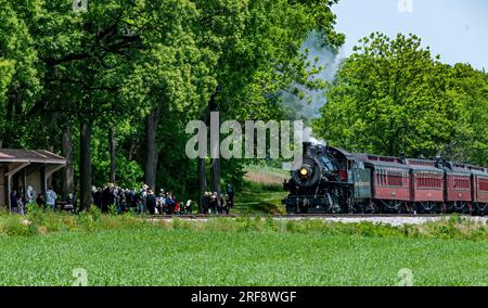Ronks, Pennsylvanie, le 18 mai 2023 - vue d'un train à vapeur antique s'approchant d'une petite gare pour ramasser un groupe de passagers par une journée ensoleillée Banque D'Images
