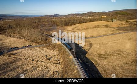 Vue aérienne d'un train de passagers à vapeur qui arrondit une courbe, qui dégage de la fumée et de la vapeur lors d'une Sunny hiver Banque D'Images