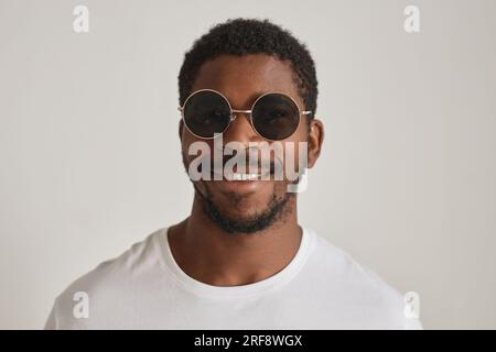 Portrait minimal vue de face homme noir portant des lunettes de soleil sur fond blanc Banque D'Images