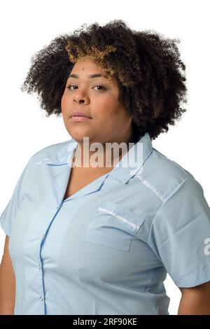 Vertical taille vers le haut portrait de jeune femme médicale afro Latina en uniforme bleu, regardant la caméra avec sérieux et sur fond blanc. Banque D'Images