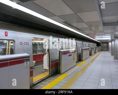 Un train du métro de Tokyo arrive au quai et les portes du wagon sont ouvertes pour que les passagers descendent. Banque D'Images