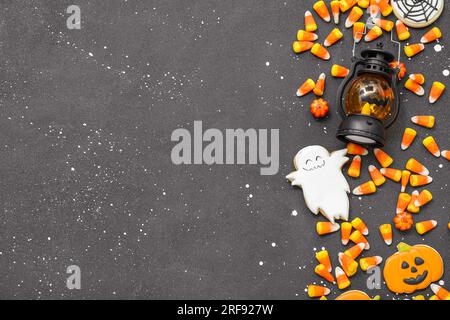 Savoureux cors de bonbons Halloween, lanterne et biscuits sur fond sombre Banque D'Images