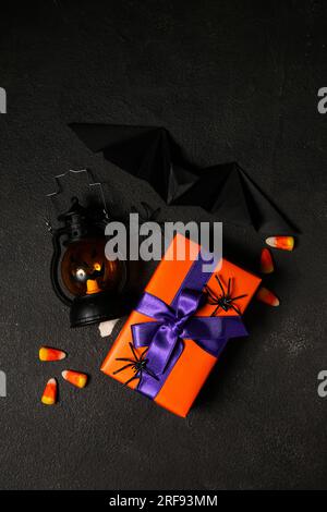 Belle boîte cadeau, cors de bonbons savoureux et lanterne pour Halloween sur fond sombre Banque D'Images