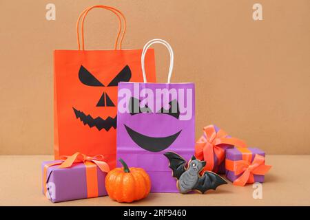 Composition avec des sacs à provisions, des boîtes cadeaux et un cookie savoureux pour Halloween sur fond beige Banque D'Images