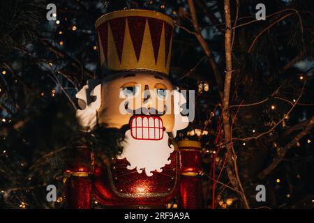 Jouet de Noël énorme casse-noisette en bois avec lumières de guirlande de soirée. Décor festif, détails extérieurs du nouvel an hiver Banque D'Images