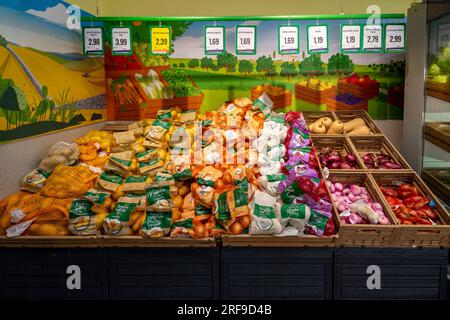 Italie - 29 juillet 2023 : pommes de terre et oignons de différents types en emballages exposés sur un étal dans un supermarché italien Banque D'Images