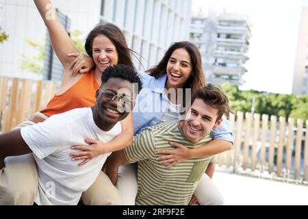 Groupe d'amis multiculturels joyeux réunis célébrant et serrant le centre-ville en plein air. Banque D'Images