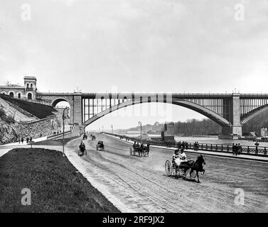 New York, New York : c. 1901 vue du Harlem River Speedway avec le Washington Bridge en arrière-plan. Il était initialement ouvert uniquement aux voitures et aux sulkies afin que les riches puissent faire défiler leurs chevaux de Trotting sur la route de terre de 2,5 km. Les piétons, les cavaliers et les cyclistes étaient interdits. Banque D'Images