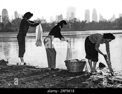New York, New York : 1949 Une pénurie d'eau à New York fait que ces trois jeunes femmes lavent leurs vêtements dans l'un des lacs de Cantral Park. Banque D'Images