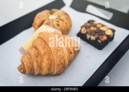 Pain à l'ail au fromage à la crème coréen, croissant au fromage de jambon et brownies au chocolat sur un plateau de service dans un café-pâtisserie ou un café-restaurant. Banque D'Images