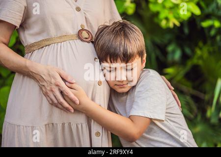 Un moment réconfortant capturé dans le parc alors qu'une femme enceinte après 40 partage un lien spécial avec son fils adolescent, embrassant la beauté de la mère Banque D'Images