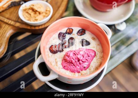 Petit-déjeuner avec porridge cuit frais servi avec cerise sèche avec sorbet fraise dans un bol. Assortiment de tranches de pain sur une planche de bois. Servi avec Banque D'Images