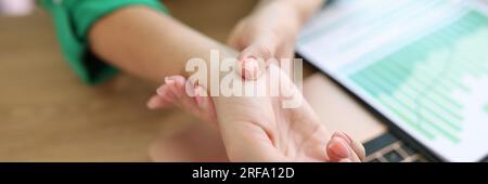 Gros plan du bras de la femme tenant son poignet douloureux causé par un travail prolongé sur l'ordinateur. Banque D'Images