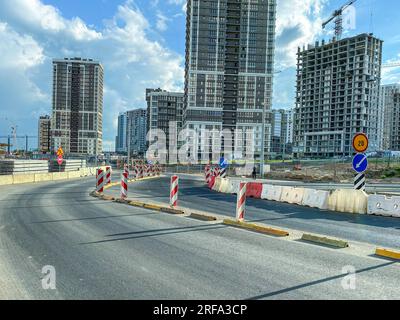 construction d'un nouveau microquartier en centre-ville. grandes maisons de verre à côté d'une route en béton gris. pose des communications dans la ville. Banque D'Images