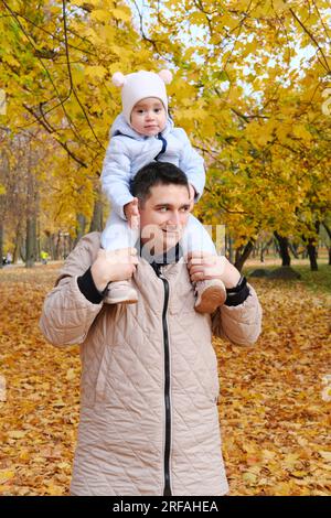 Portrait d'un père portant sa mignonne petite fille sur les épaules, bébé et papa avec plaisir passer du temps ensemble à l'extérieur, vie de famille heureuse. Banque D'Images