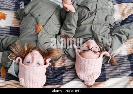 Deux sœurs jumelles heureuses s'allongent sur une couverture dans un parc d'automne. Les filles sourient et regardent la caméra. Vue d'en haut. Photo horizontale Banque D'Images