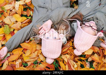 Portrait de deux mignonnes filles sœurs jumeaux couchées sur les feuilles au parc d'automne. Photo horizontale Banque D'Images