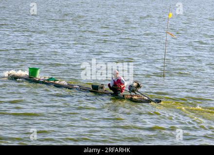 Klaten, Indonésie - 30 juillet 2023 : pêcheur sur un bateau traditionnel en bambou dans le lac Rowo Jombor, Klaten, Indonésie Banque D'Images