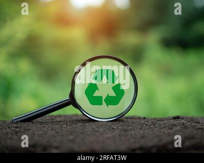 Concepts de réduction des déchets, pollution, réutilisation, utilisation efficace des ressources. Symbole de recyclage dans la loupe sur fond de nature. Banque D'Images