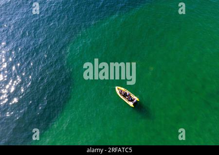 Image aérienne de drone de côte jaune dans l'eau de mer verte plus près du rivage où la lumière se reflète sur le sable avec l'eau plus profonde et bleue au-delà Banque D'Images