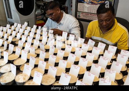 Le négociant en riz expose une variété d'échantillons de riz dans un magasin de gros, à Guwahati, Assam, en Inde, le 2 août 2023. Pénuries de riz non basmati causées par les pluies et la sécheresse en Inde, le gouvernement indien interdit les exportations de riz pour assurer l'approvisionnement intérieur. Crédit : David Talukdar/Alamy Live News Banque D'Images