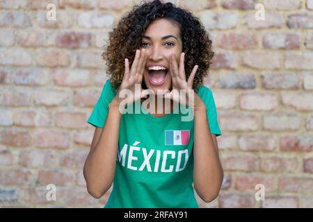 Criant fan de football féminin mexicain avec maillot de football vert Banque D'Images
