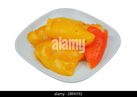 Poivre fermenté dans une assiette isolée sur fond blanc. Paprika mariné. Banque D'Images