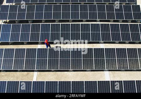 HANGZHOU, CHINE - 2 AOÛT 2023 - des employés d'une société d'alimentation électrique vérifient les installations de production d'énergie photovoltaïque sur le toit d'une école primaire Banque D'Images