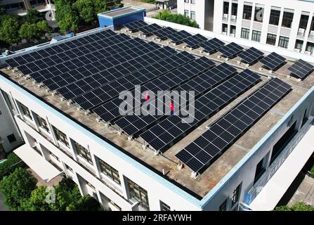 HANGZHOU, CHINE - 2 AOÛT 2023 - des employés d'une société d'alimentation électrique vérifient les installations de production d'énergie photovoltaïque sur le toit d'une école primaire Banque D'Images