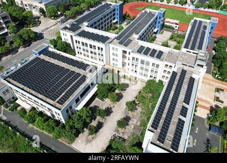 HANGZHOU, CHINE - 2 AOÛT 2023 - des employés d'une société d'alimentation électrique vérifient les installations de production d'énergie photovoltaïque sur le toit d'une école primaire Banque D'Images