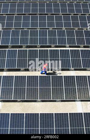 HANGZHOU, CHINE - 2 AOÛT 2023 - des employés d'une société d'alimentation électrique vérifient les installations de production d'énergie photovoltaïque sur le toit d'une école primaire Banque D'Images