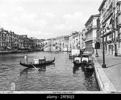 Venise - 1870 ca Une gondole longe le Grand Canal près du pont du Rialto, le plus ancien pont de Venise pour permettre la traversée à pied du Grand Canal. Il relie la zone la plus touristique du centre historique de Piazza San Marco au célèbre marché du Rialto. Fabriqué à l’origine en bois et maintenant en pierre, ce chef-d’œuvre d’ingénierie et d’architecture a subi deux effondrements et un incendie. Conçu par l'architecte Antonio Da Ponte, les travaux de construction ont commencé à la fin de 1500.le pont est de 48 mètres de long et 22 mètres de large, se compose de 1 grands arcs de 28 mètres et il ya 3 vols de Banque D'Images