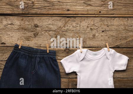 Short blanc de croissance de bébé et de denim accroché avec des pinces à vêtements avec espace de copie sur fond en bois Banque D'Images