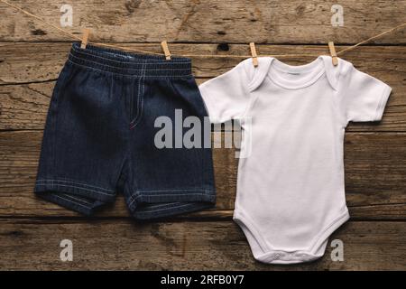 Short blanc de croissance de bébé et de denim accroché avec des pinces à vêtements avec espace de copie sur fond en bois Banque D'Images