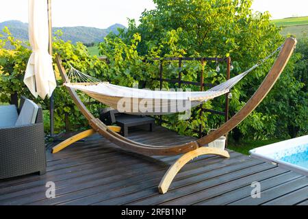 Hamac suspendu sur la terrasse en bois avec table à un vignoble. Concept de coin paradis dans le quartier industriel de la grande ville. Banque D'Images