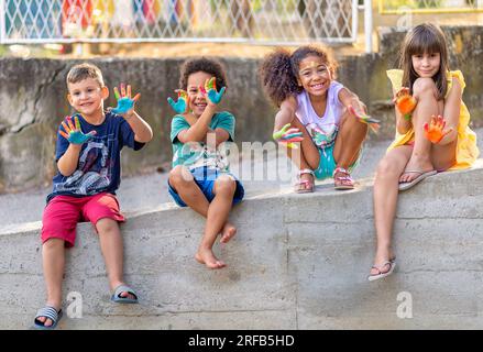 groupe d'enfants multiculturels joyeux jouant ensemble, montrant des mains peintes Banque D'Images