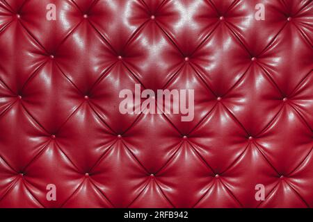 Gros plan texture de fond en cuir véritable rouge, style rétro classique Chesterfield, rembourrage de meubles avec motif de diamant profond et boutons Banque D'Images