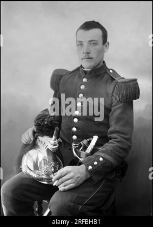 Portrait d'un jeune militaire, avec son casque de cuirassier sur les genoux. A l'abbaye de Septfontaines, Bourmont (haute Marne). Photographie, vers 1870-1886, de Paul Emile Theodore Ducos (1849-1913). Banque D'Images