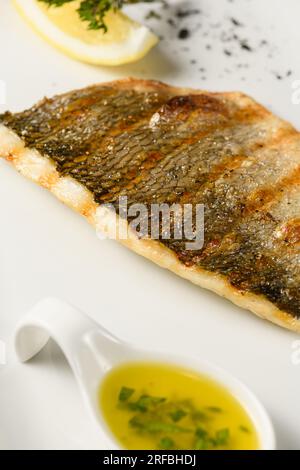 Appétissant filet de poisson dorado grillé sur une assiette blanche. Gros plan. Banque D'Images