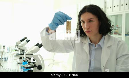 Chimiste homme scientifique tenant des tubes à essai avec des grains dans le gros plan de laboratoire Banque D'Images