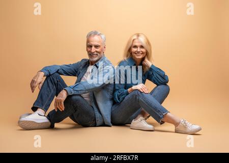 Homme âgé positif et femme dans le décontracté assis sur beige Banque D'Images