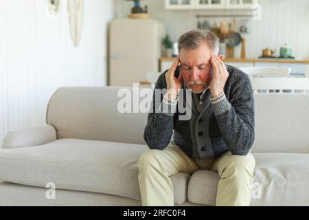 Maux de tête. Malheureux homme âgé d'âge moyen souffrant de maux de tête malade frottant les tempes à la maison. Vieux grand-père aîné mature touchant les temples éprouvant du stress. Homme sentant mal à la tête Banque D'Images