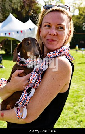 Jeune femme avec son chien lors des célébrations pour le couronnement du roi Charles, Alton, Hampshire, Royaume-Uni. Banque D'Images