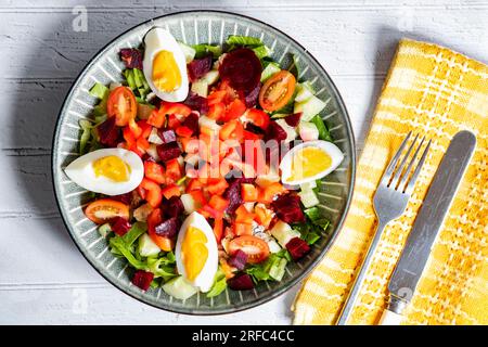 Une salade diététique méditerranéenne saine servie dans un bol contenant des ingrédients colorés, notamment des tomates poivrons, des betteraves, des œufs et de la laitue. Banque D'Images