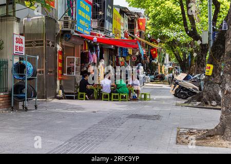 Hanoi, Vietnam - 28 mai 2023 : une rue vibrante bourdonne de vie alors que les habitants se rassemblent dans un restaurant animé au bord de la route. Ils sont assis sur des tabourets bas, partageant la rire Banque D'Images