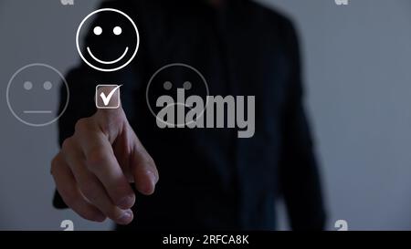 Service à la clientèle et concept de satisfaction, homme d'affaires pressant émoticône visage smiley sur l'écran tactile virtuel. Sur le visage Happy Smiley. Banque D'Images