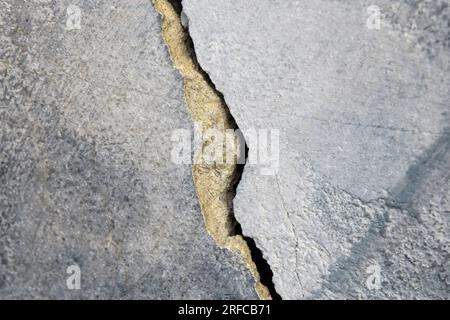 Grosse fissure sur le vieux mur de plâtrage peint. Longue fissure d'enroulement dans la surface d'un vieux bâtiment. Espace de copie. Mise au point sélective. Banque D'Images